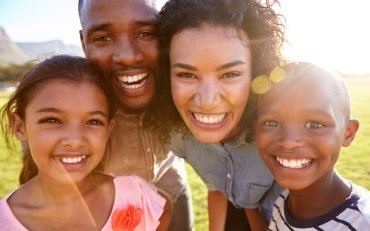 laughing-black-family-outdoors-close-up-back-lit-PPCMZD4.jpg